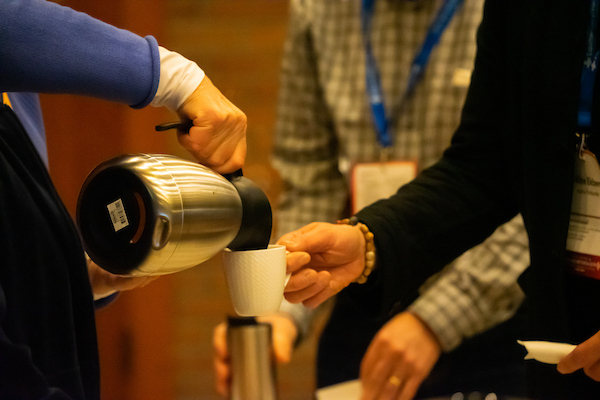 En samling där en person serverar kaffe åt en annan.