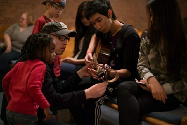 Unga man får hjälp att stämma sin gitarr