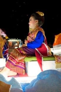 Liten flicka sittandes på en vagn i paraden