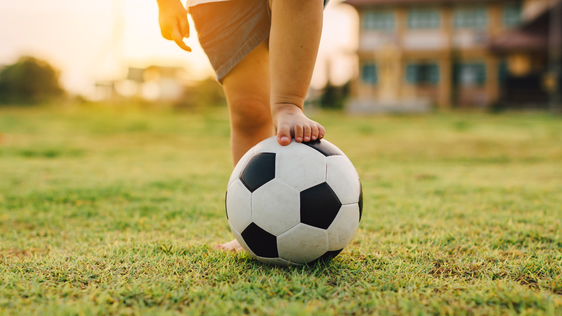 Ett barn som står med foten på en fotboll.